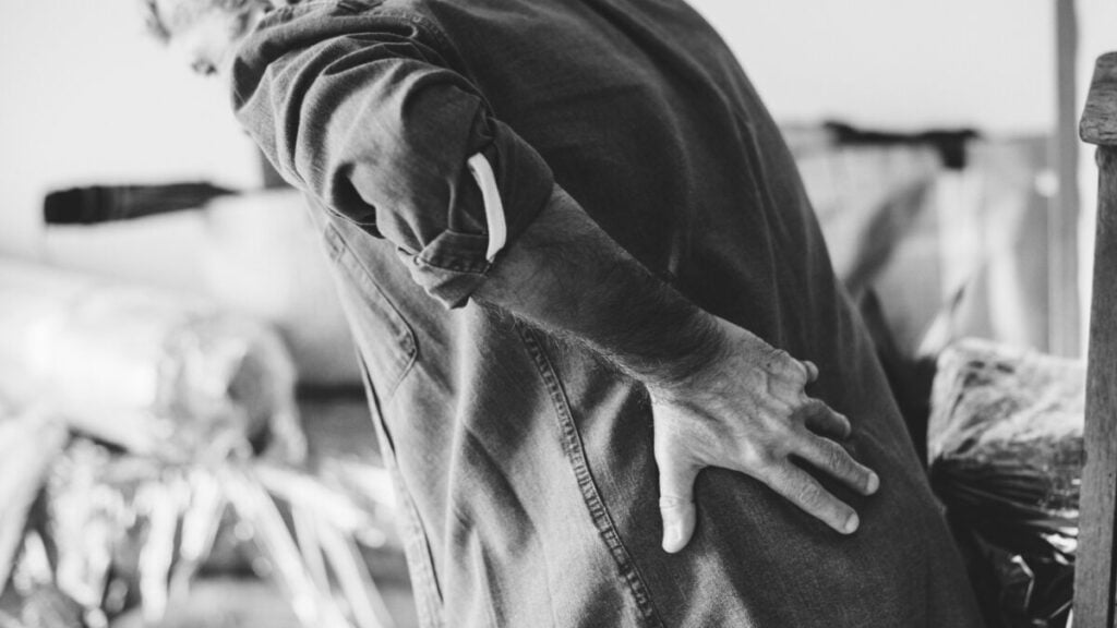 A man holding his back in pain, displaying the struggle with chronic low back pain