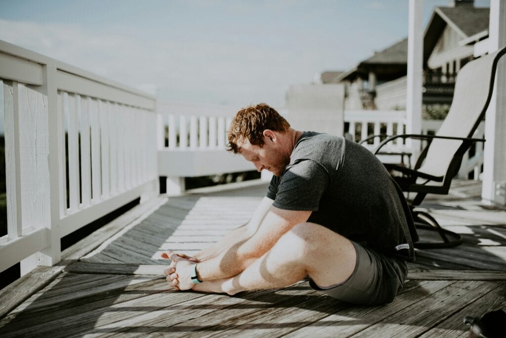 Man doing morning exercise demonstrating Tailor Pose, Baddha Konasana or Butterfly Pose for hip mobility and stretching the adductor muscles