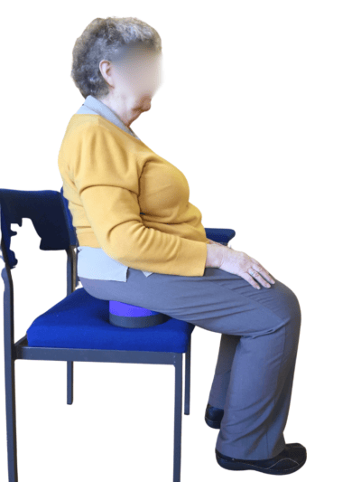 A woman with multiple sclerosis sitting upright on a chair using the Standard Buttafly for stability in chair yoga